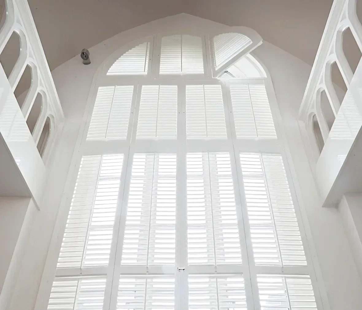 Hoog boograam in een oud gebouw met witte shutters die de vorm van de boog volgen
